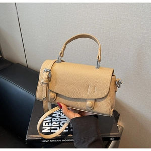 Close-up of litchi texture on beige small square bag with stitching and round buckle