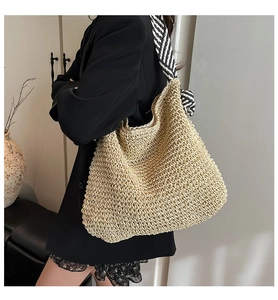 Détail du sac cabas en paille tissée avec un foulard rayé noir et blanc chic sur l'anse