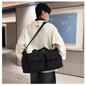 Detailed view of black travel bag with double front buckle pockets and adjustable shoulder strap