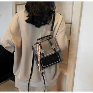 Détail d'un sac à dos vintage avec des clous en étoile et un pendentif tissé rose