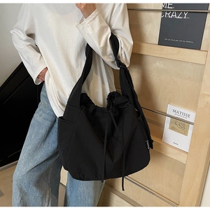Detail of black canvas crossbody bag with drawstring closure and wide adjustable strap