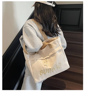 Detailed shot of large beige canvas tote bag with yellow embroidery and brown straps