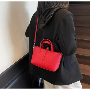 Detailed view of a red lychee pattern leather tote bag worn as a crossbody bag