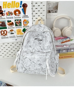 Detailed view of the gray marble pattern backpack with logo on a modern white desk