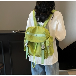 Detail of green nylon backpack showing silver buckle and drawstring flap closure