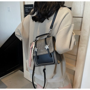 Détail du sac bandoulière en toile avec boucles étoiles et rabat en cuir noir