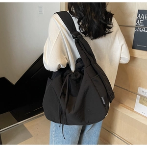 Detail of black cloud-shaped canvas bag with drawstring side and wide shoulder strap