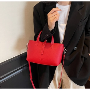 Macro shot of red lychee grain leather handbag with adjustable long shoulder strap