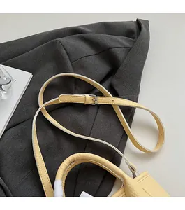 Detail of yellow lychee grain leather handbag with adjustable silver buckle shoulder strap