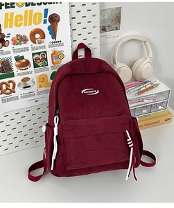 Detail of burgundy backpack with QIJAOYE embroidery and white rope zipper pulls