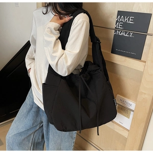 Black nylon drawstring shoulder bag featuring a large capacity and adjustable strap