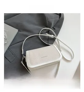 Detailed close-up of white woven leather texture on a minimalist small square crossbody bag