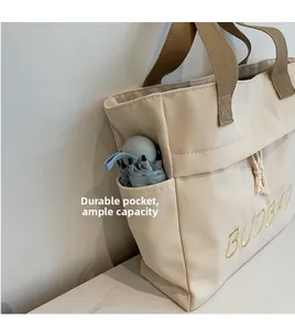 Detail view of beige canvas tote bag side pocket holding a folding umbrella