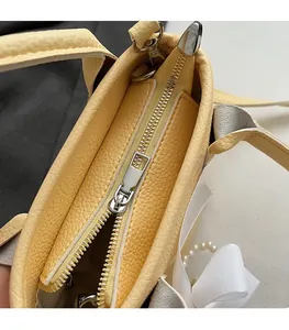 Detailed macro view of the smooth silver zipper and yellow litchi leather bucket bag