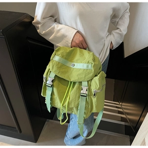 Detail of light green nylon backpack with metal buckle and drawstring closure in use