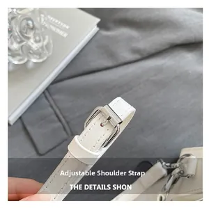Detail of adjustable white leather shoulder strap with silver buckle and fine stitching