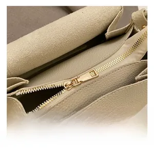 Detail view of golden metal zipper and hardware on beige lychee textured leather bag