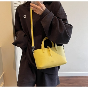 Detail of bright yellow leather bucket bag with top handle and adjustable shoulder strap