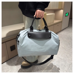 Detailed view of light blue nylon travel bag with leather handles shown in a home setting