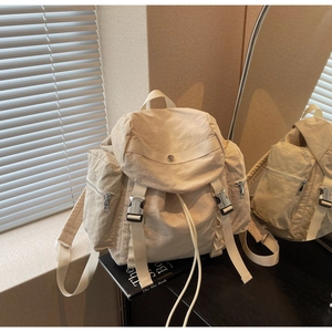 Detail of cream white nylon backpack with buckle closure and drawstring in lifestyle setting