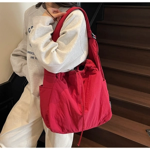 Detail of red drawstring canvas shoulder bag with large capacity and side pockets