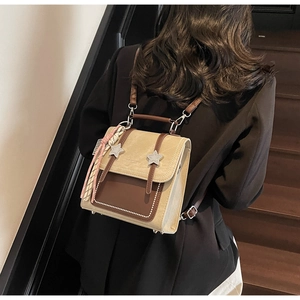 Detail view of vintage beige backpack with star studs and fringe tassel on black blazer