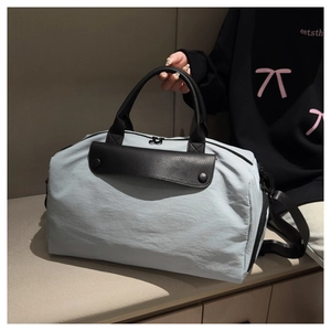 Close-up of light gray travel bag with black leather flap and metal buckle detail