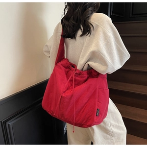 Detail of red large capacity crossbody bag with drawstring closure and brand label