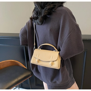 Close-up of beige lychee grain leather mini handbag with top handle and crossbody strap