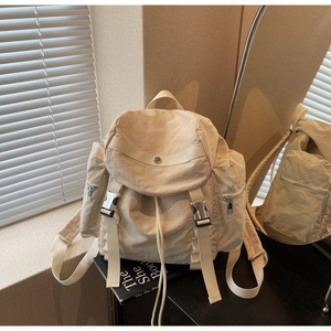 Detail of cream nylon backpack with metallic buckle closure and side zipper pockets