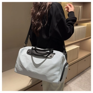 Gray-blue nylon travel bag shown on shoulder in library setting for size comparison