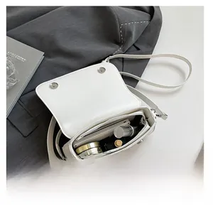 Detail of white rectangular crossbody bag showing interior capacity with cosmetics