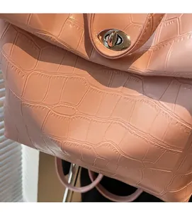 Detalle de mochila rosa con textura de cocodrilo en relieve y cierre de metal plateado