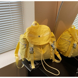 Detail shot of bright yellow nylon backpack featuring functional pockets and metal buckles