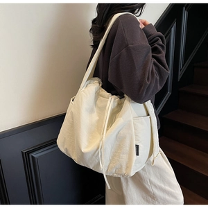 Detail of white nylon tote bag with drawstring closure and side pocket on female model