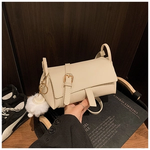 Detail of off-white lychee texture leather handbag with golden hardware and plush ball