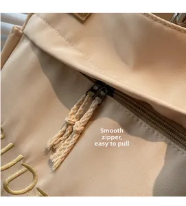 Detail of smooth nylon zipper with woven cord puller and gold embroidery on beige canvas tote