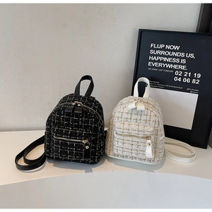 Détail de mini sacs à dos en tweed noir et beige avec sangles en cuir et zips dorés