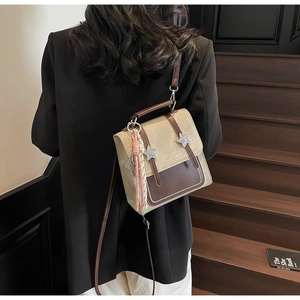 Détail d'un sac à dos vintage beige et marron avec étoiles argentées et pendentif à pampilles