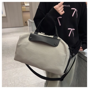 Detail of grey travel bag with black leather handles and adjustable nylon shoulder strap
