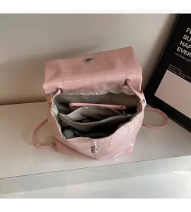 Vista interior de la mochila rosa con relieve de cocodrilo mostrando capacidad y bolsillos
