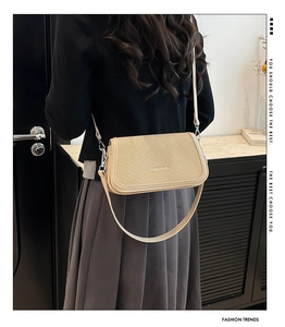 Detailed view of beige woven texture and silver hardware on a crossbody handbag