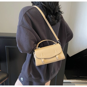 Borsa a mano beige in pelle martellata con tracolla indossata da una modella