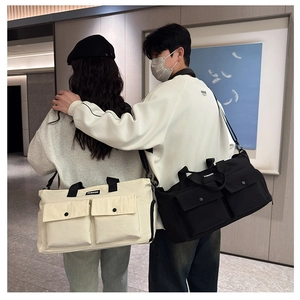 Large travel duffel bag with dual pockets shown in beige and black by a model