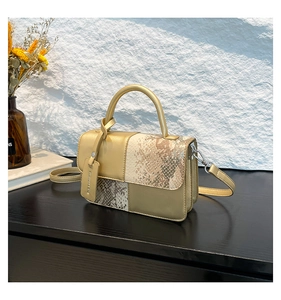 Détail du sac à main doré champagne avec texture serpent et étiquette logo métallique