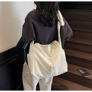 Detail of cream canvas tote bag with drawstring closure and practical side pockets