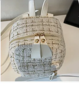 Vue détaillée des fermetures éclair dorées sur un sac à dos en tweed blanc pour femme