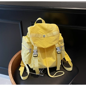 Close-up of bright yellow nylon backpack with silver buckle on a leather chair