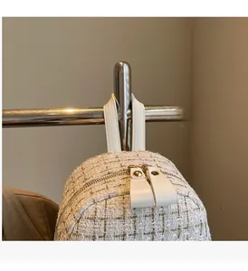 Détail d'un sac à dos en tweed avec poignée en cuir et surpiqûres dorées fines