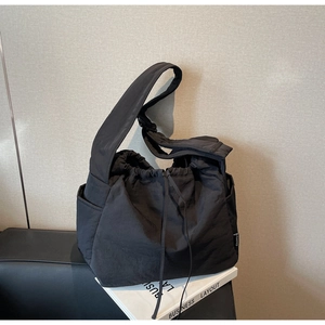 Detail of black drawstring nylon shoulder bag with wide strap and spacious side pocket